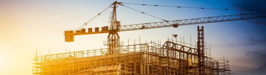 Estrutura de obra com guindaste e andaimes representando gestão digital da construção